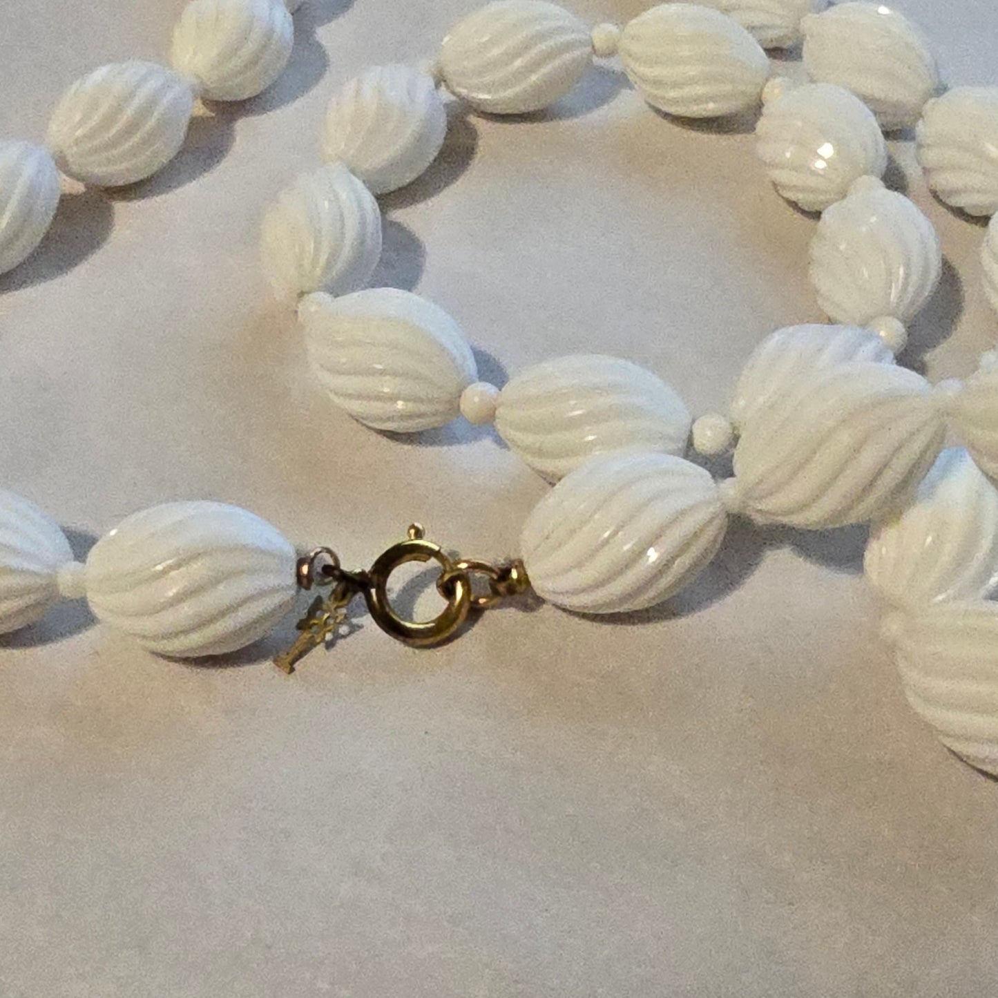 Close-up of a white beaded necklace with a clasp on a light background