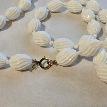 Close-up of a white beaded necklace with a clasp on a light background