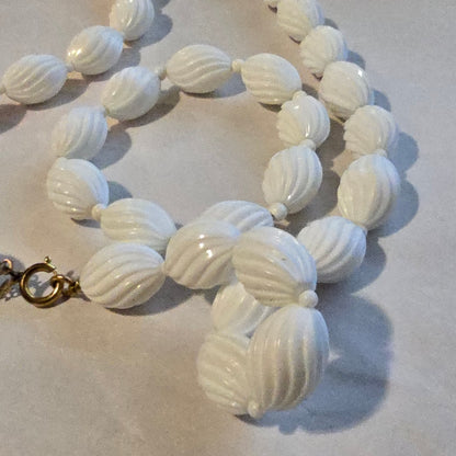 White shell-shaped beads on a necklace against a light background