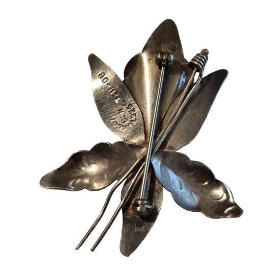 Silver butterfly brooch on a light gray background