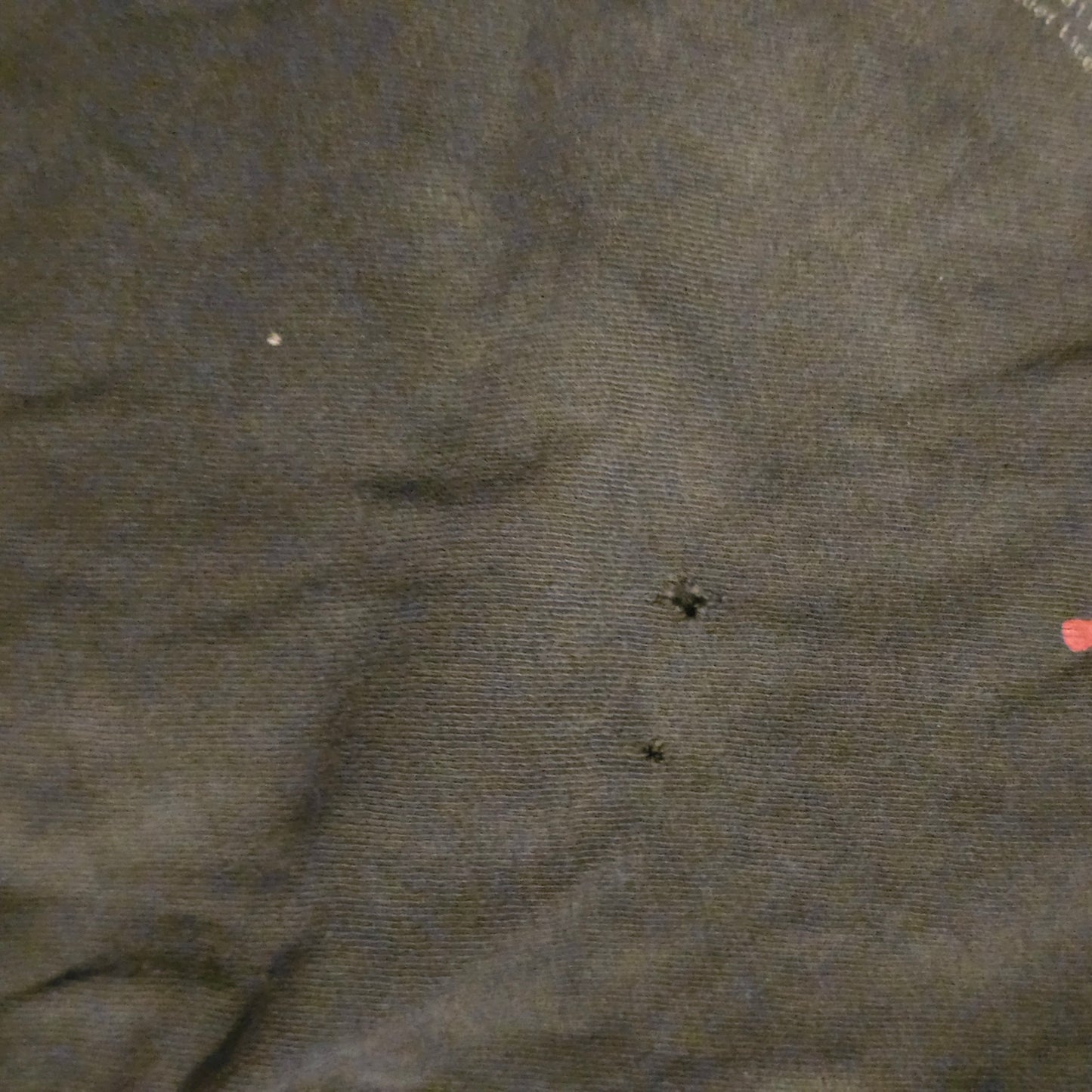 Close-up of dark fabric with small holes and imperfections