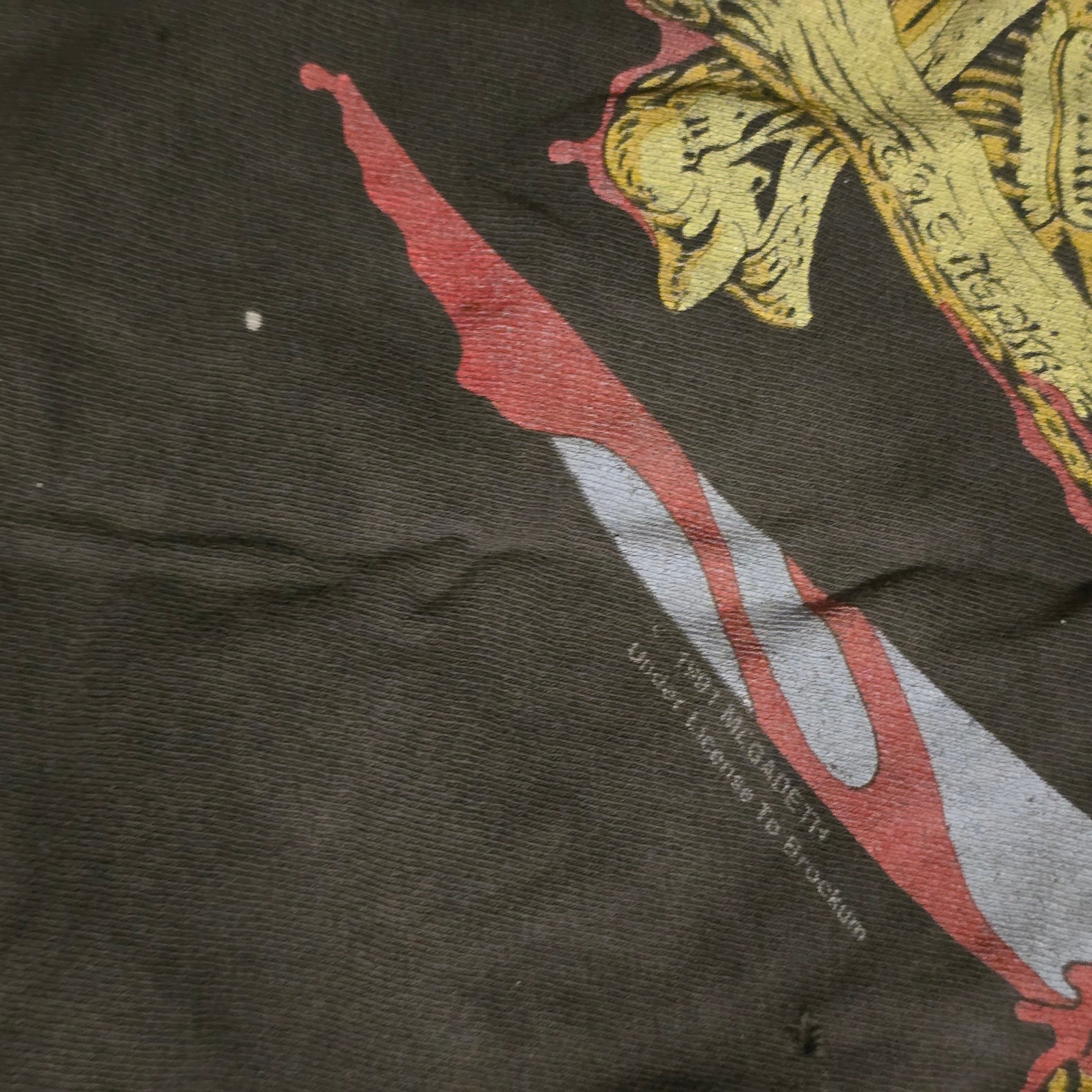 Close-up of a dark fabric with embroidered designs, including a red and white stripe and gold floral pattern.
