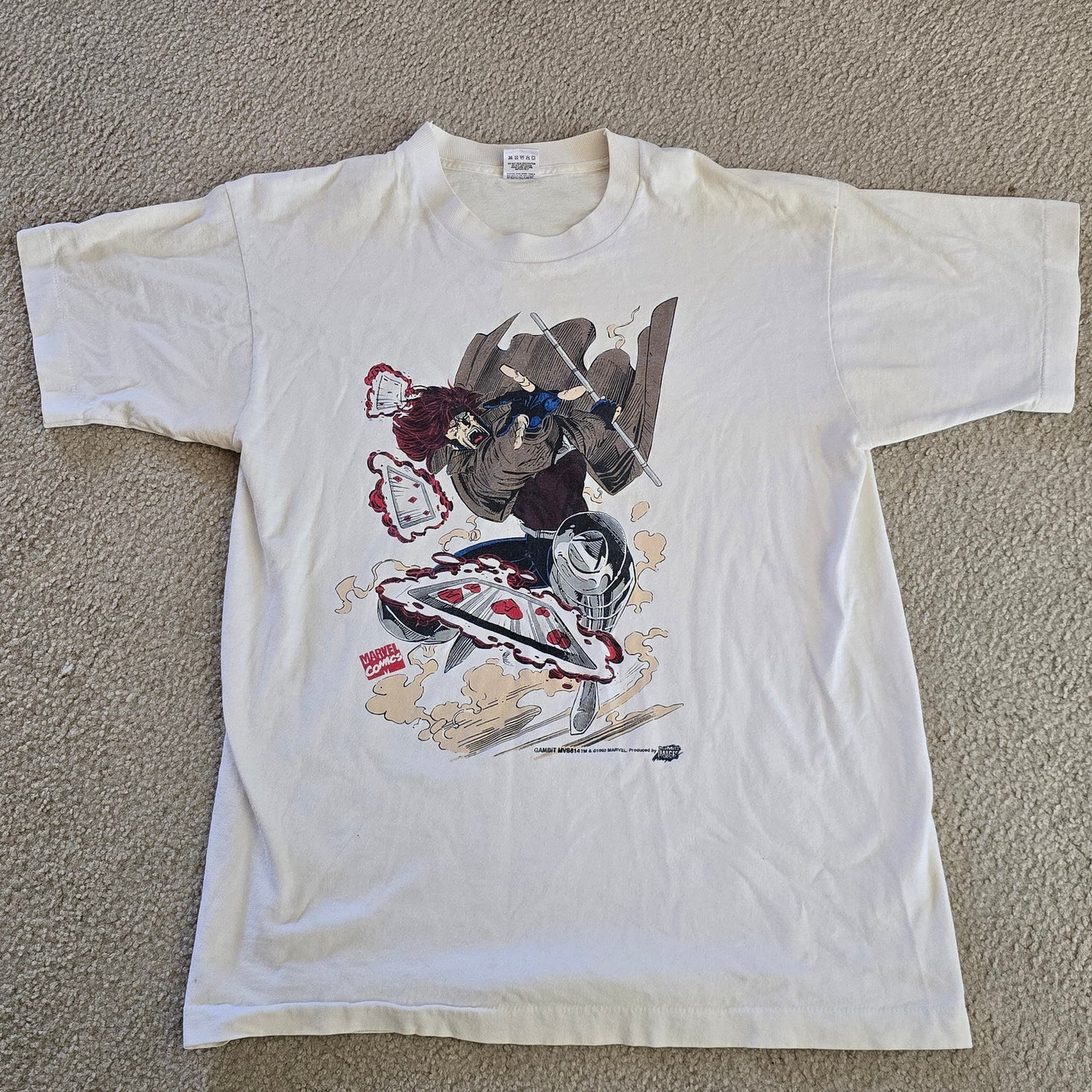 White t-shirt with colorful graphic design on a beige carpet