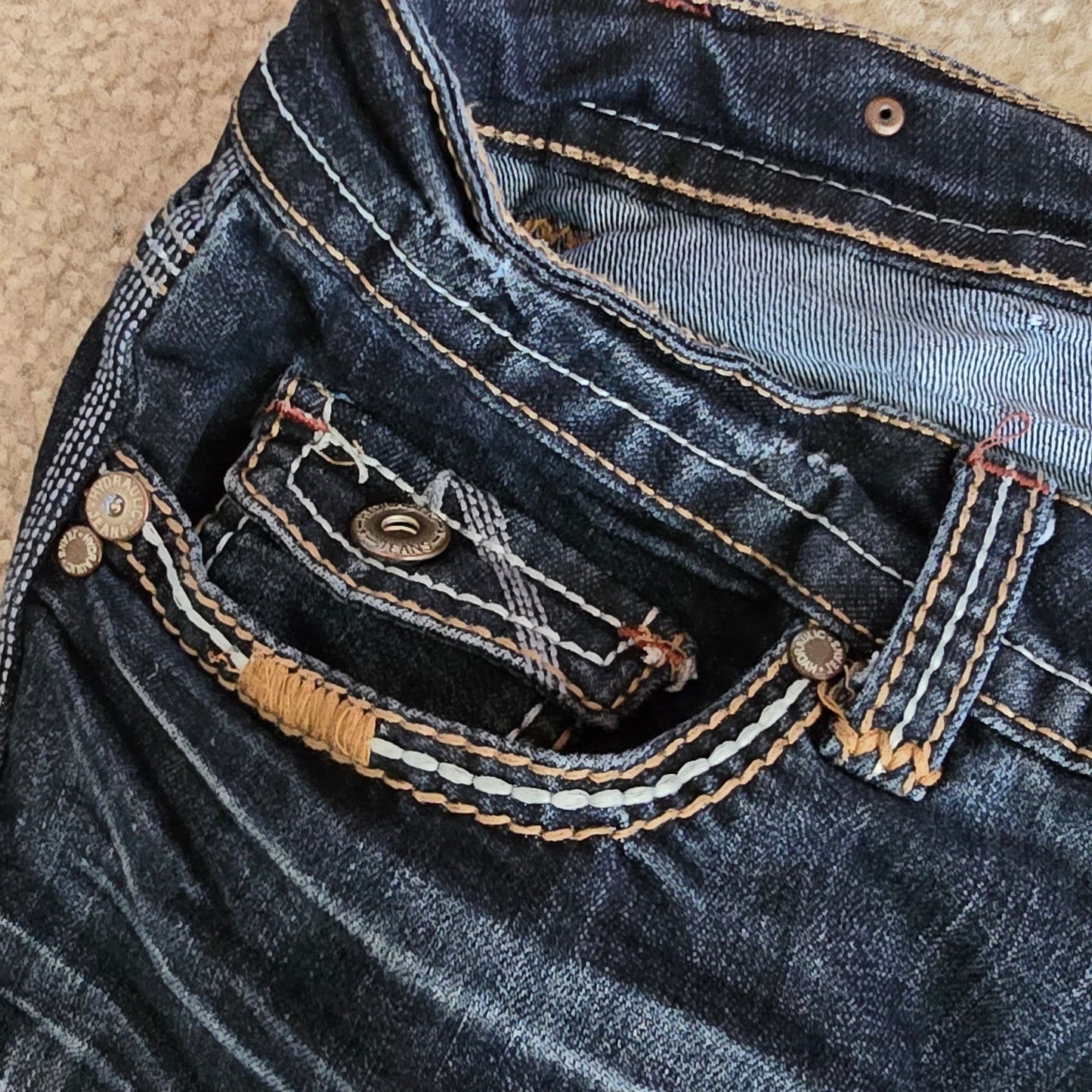Close-up of blue denim fabric with stitching details on a beige background