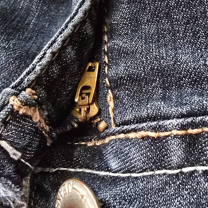 Close-up of a button and zipper on a pair of dark blue jeans.