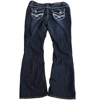 Folded pair of dark blue jeans on a beige carpet