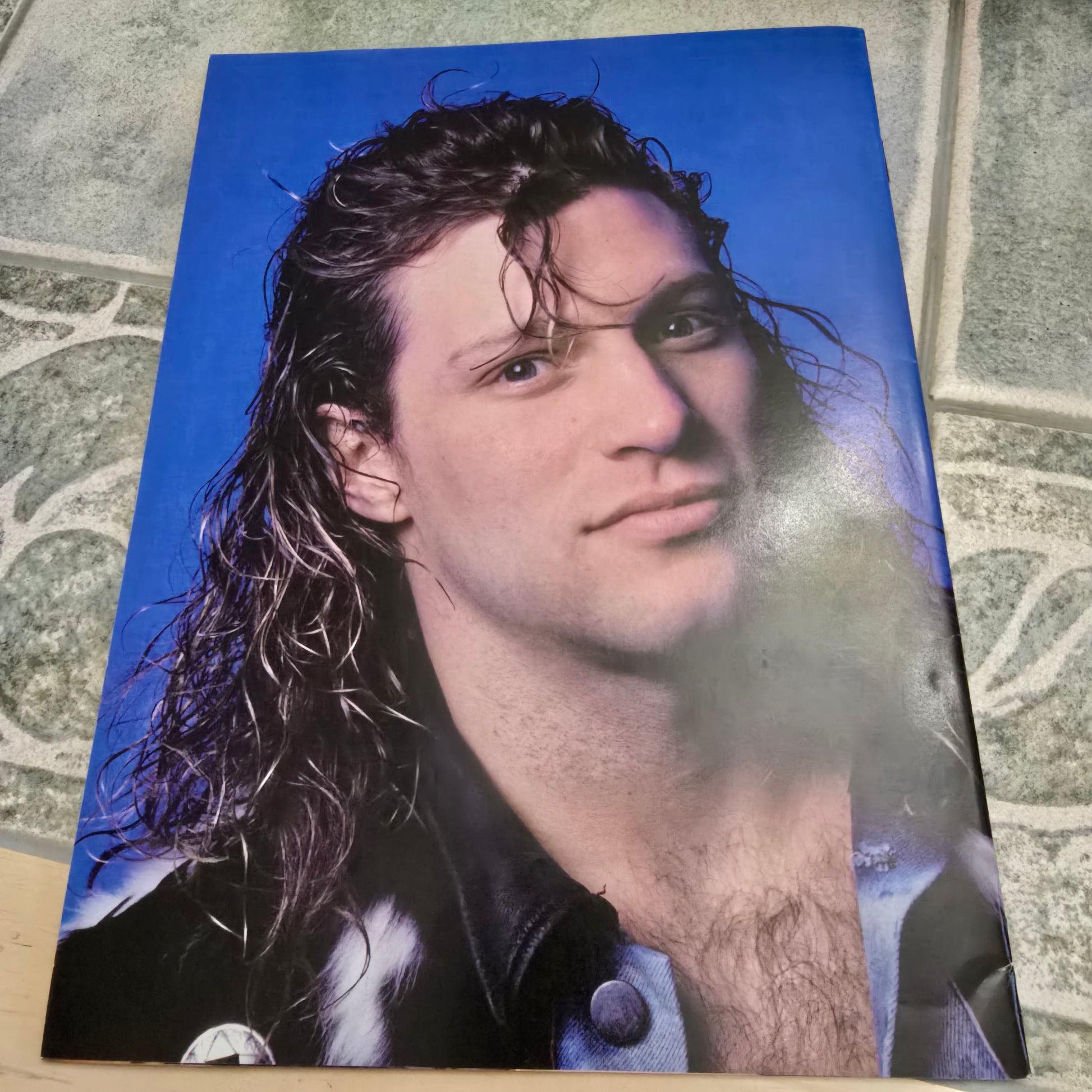 Poster of a person with wet hair on a blue background, lying on a textured surface.