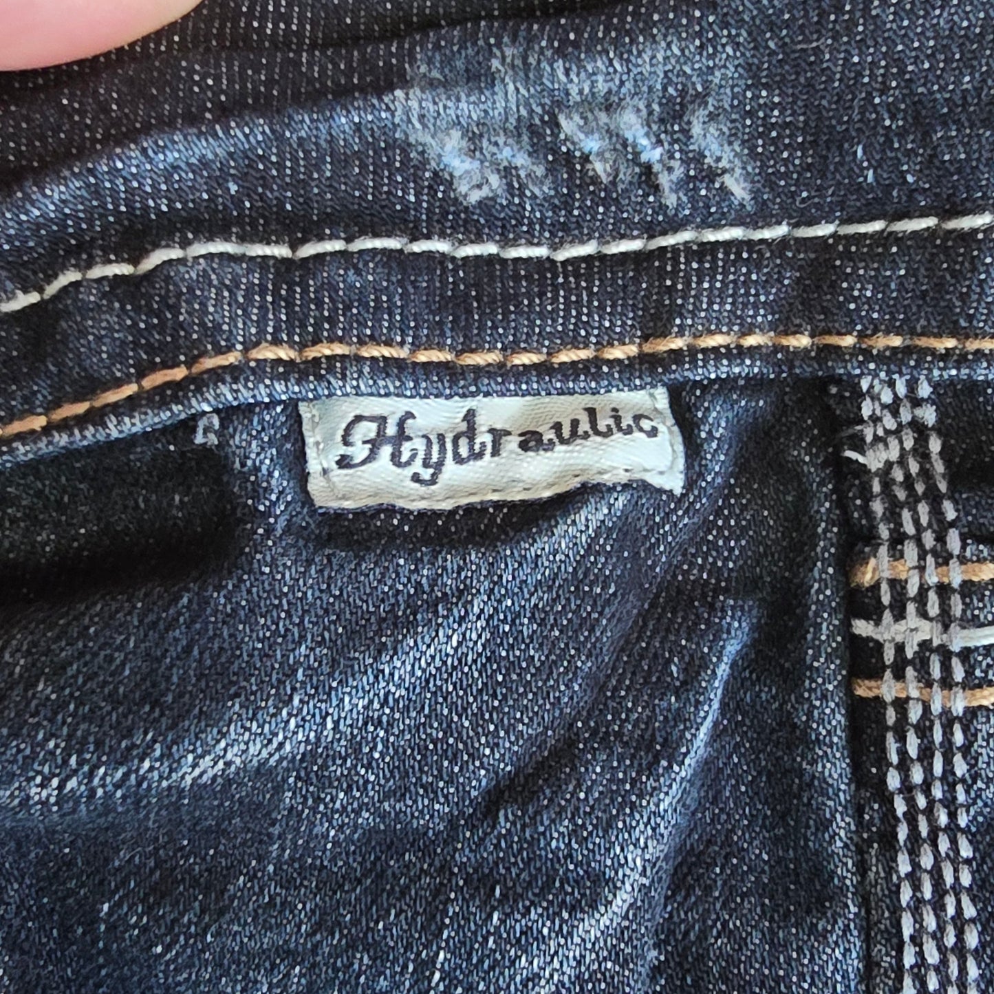 Close-up of a denim fabric with a brand label on a dark blue background